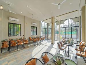 a restaurant with tables and chairs and windows at Palette Hotel Orient Greenz by CheckIn, Pench in Khawāsa