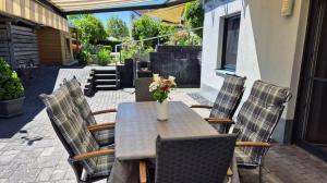 a table with chairs and a vase of flowers on a patio at Ferienwohnung BungertOase in Saarburg
