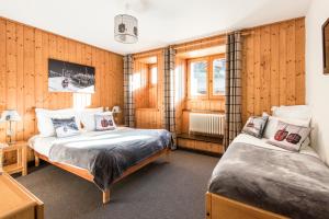 two beds in a room with wooden walls at Chalet-hôtel Gai Soleil in Les Contamines-Montjoie