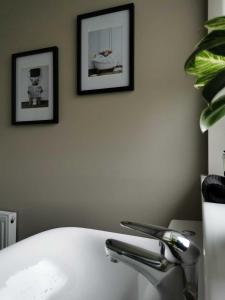 a bathroom with a white tub and two pictures on the wall at Limekilns House in Clydebank