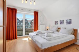 two beds in a bedroom with orange curtains and a window at Möwenblick in Norddeich