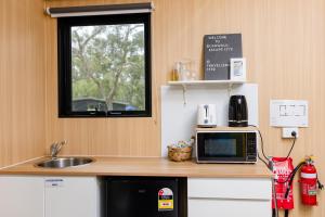 a kitchen with a counter with a microwave and a sink at Bushwalk Escape 1770 in Agnes Water