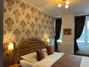 a bedroom with a bed with a brown headboard and curtains at Karmia Boutique in Piatra Neamţ