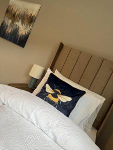 a bed with a pillow with a bee on it at Knowes Apartment in Duntocher