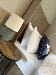 a bed with pillows and a table with a lamp at Knowes Apartment in Duntocher