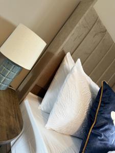 a bed with a lamp and two pillows on it at Knowes Apartment in Duntocher