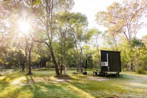 a black box sitting in a field next to a tree at Bushwalk Escape 1770 in Agnes Water