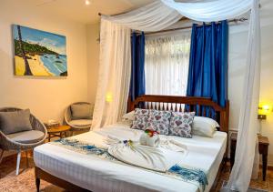 a bedroom with a bed with blue curtains at Buisson Guesthouse in La Digue