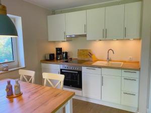 a kitchen with white cabinets and a wooden table at Wohnung Wiesenblick Whg 1 in Böhl