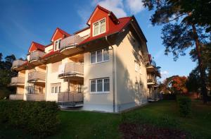 ein großes weißes Gebäude mit rotem Dach in der Unterkunft Ferienwohnung Christiane in der Villa zum Kronprinzen direkt gegenüber der SaarowTherme in Bad Saarow