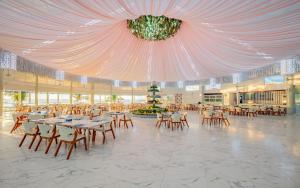 a banquet hall with tables and chairs and a chandelier at Carmelina Beach Resort Ho Tram in Ho Tram
