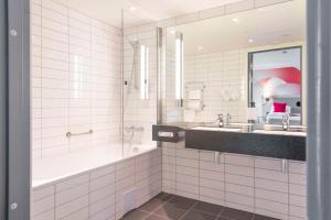 a bathroom with a tub and a sink and a mirror at Scandic Meyergården in Mo i Rana