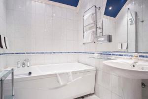 a white bathroom with a tub and a sink at Scandic Meyergården in Mo i Rana