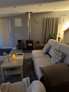 a living room with a couch and a table and a fireplace at Hot tub Retreat, Linlithgow in Linlithgow