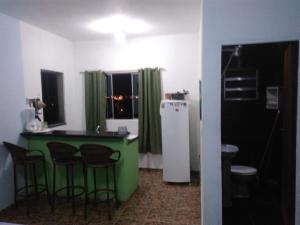 a kitchen with a green counter and stools at Ilha Céu Sol in Ilhabela