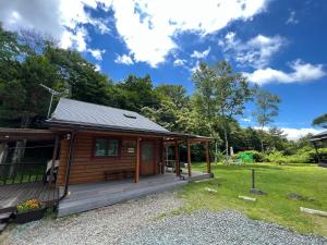 a log cabin with a porch and a lawn at Family Cottage Pokhara in Yamanakako