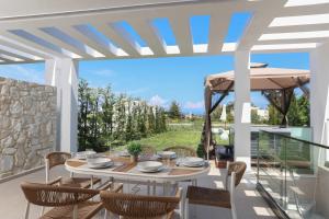 a patio with a table and chairs and a stone wall at Aquaris in Hanioti