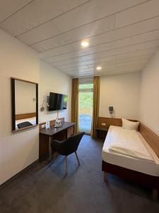 a bedroom with a bed and a desk and a mirror at BSW Ferienhotel Lindenbach in Bad Ems