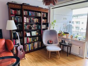 a room with a chair and a book shelf with books at Beach & City Fun plus Elevator & Free Parking in Hellerup
