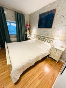 a bedroom with a white bed and a wooden floor at Beach & City Fun plus Elevator & Free Parking in Hellerup
