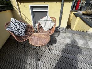 three wicker chairs and a table on a patio at Moderne und gemütliche Wohnung in Herzogenrath