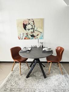 a dining room table with two chairs and a painting at Moderne und gemütliche Wohnung in Herzogenrath