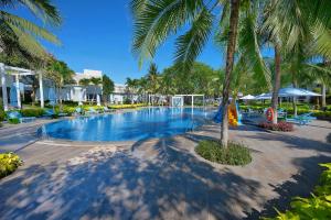 a swimming pool with palm trees in a resort at Carmelina Beach Resort Ho Tram in Ho Tram