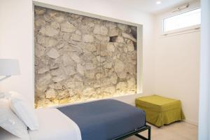 a bedroom with a stone wall next to a bed at La Casetta di Carol in Capri