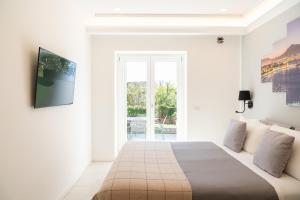 a white bedroom with a large bed and a window at La Casetta di Carol in Capri