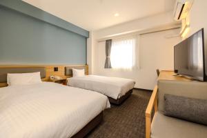 a hotel room with two beds and a flat screen tv at Kochi Sunrise Hotel in Kochi