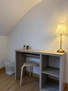 a desk with a lamp and a chair in a room at Le Petit Ussellois in Ussel