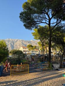 a park with a playground with a tree and mountains at Meeresblick Apartment S4 in Promajna