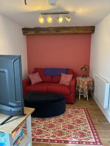 a living room with a red couch and a tv at Farm Cottage near Shrewsbury in Clive