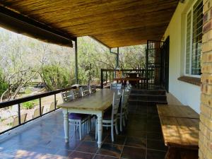 a patio with a wooden table and chairs on a balcony at Jimmy's Place in Dinokeng Game Reserve