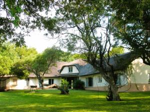 a white house with a tree in the yard at Jimmy's Place in Dinokeng Game Reserve