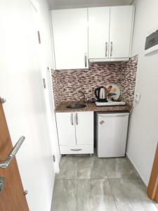 a small kitchen with white cabinets and a sink at Can Residence in Trabzon