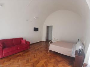 a living room with a red couch and a bed at Tursi Relais Virtus in Tursi