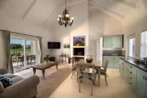 a kitchen and living room with a table and a dining room at La Jolie Dauphine Guest House in Franschhoek