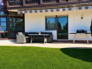 a patio with a couch and a table in front of a house at Apartment Kneer - Panoramic View & Private Garden near Black Forest & Lake Constance in Donaueschingen