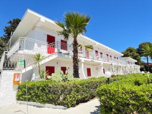 a white building with red doors and a palm tree at Bungalow 97 in Fontane Bianche