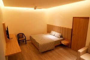 a small bedroom with a bed and a chair at Hotel Avani Grand in Zahirābād
