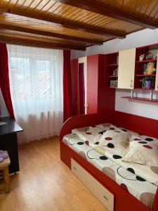 a bedroom with a large bed with red walls at Apartament Floare de Colț in Buşteni