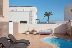 a patio with chairs and a swimming pool on a building at Casa Orquídea 7 in El Médano