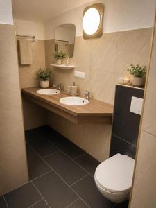 a bathroom with two sinks and a toilet and a mirror at Gästezimmer Lercher in Sankt Veit im Pongau