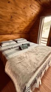 a large bed in a wooden room with a window at Chalé do Lago - Refúgio Arara Azul in Urubici