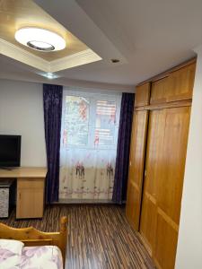 a room with a bed and a window and a television at Apartament Floare de Colț in Buşteni