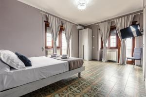 a bedroom with a bed and a tv and windows at Malù House in Fiumicino
