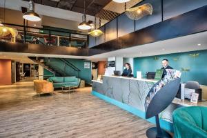 a lobby with two people standing at a counter at ibis Styles Saint Julien en Genevois accès espace aquatique UCPA Vitam INCLUS in Neydens +118 photos