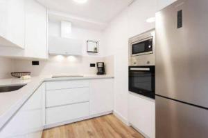a white kitchen with white cabinets and a refrigerator at Eden Rentals Olympia Sunny Seaviews in Playa de las Americas