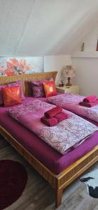 ein Schlafzimmer mit zwei Betten und lila und roten Kissen in der Unterkunft Harzspaß in Braunlage